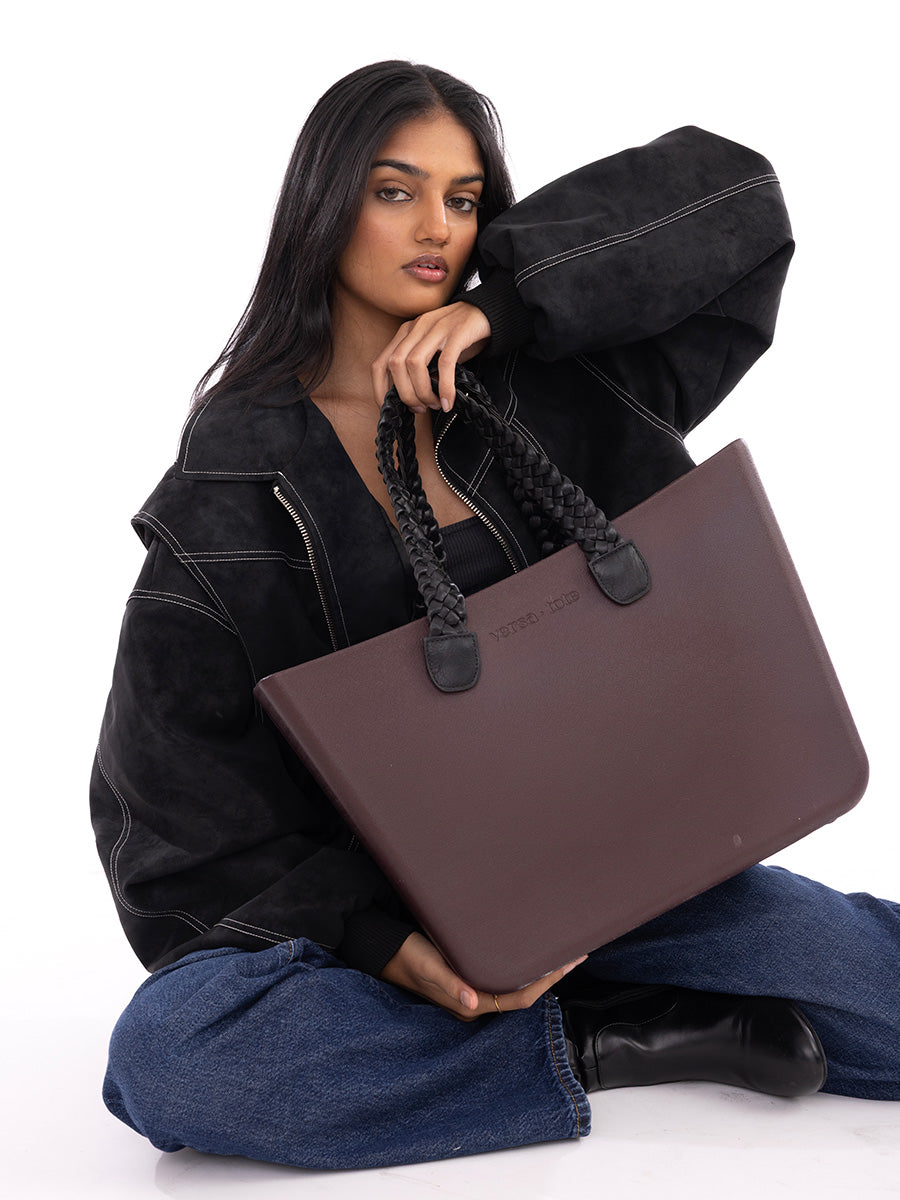 Dark brown tote bag with black handles and round snap-button details