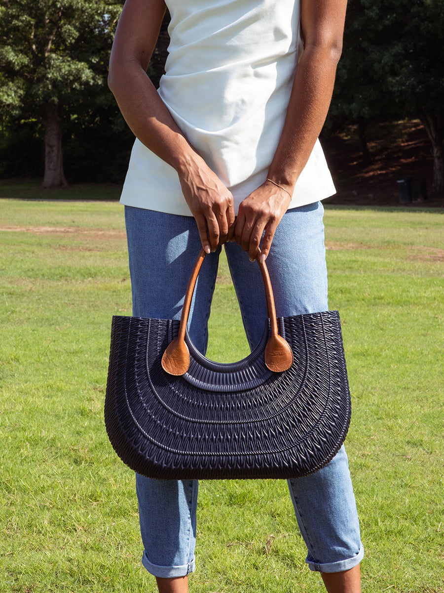 Brown vegan leather tote strap with teardrop end pads on a dark tote